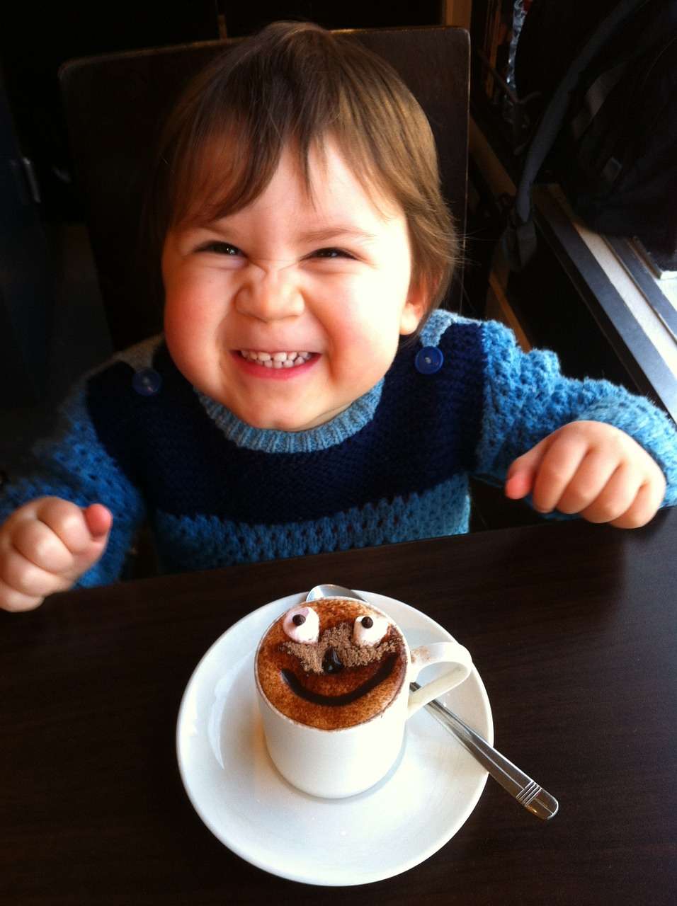 Criança brinca perto de xícara de chocolate: a dica é limitar o consumo de açúcar ou doces a pequenas quantidades