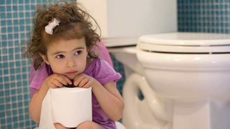 Pequena menina segura rolo de papel higiênico perto de privada: infecção urinária dos filhos preocupa os pais