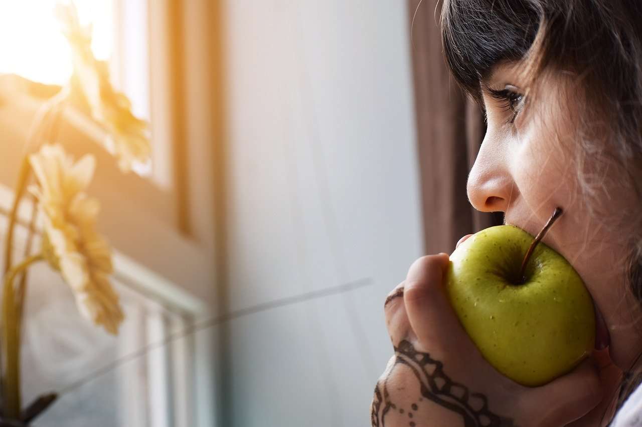 Criança come uma maçã: ser assertivo na introdução da alimentação complementar terá grande influência nos hábitos alimentares, em longo prazo.
